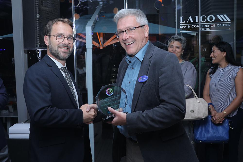 Don King smiling while receiving an ward from someone and shaking their hand